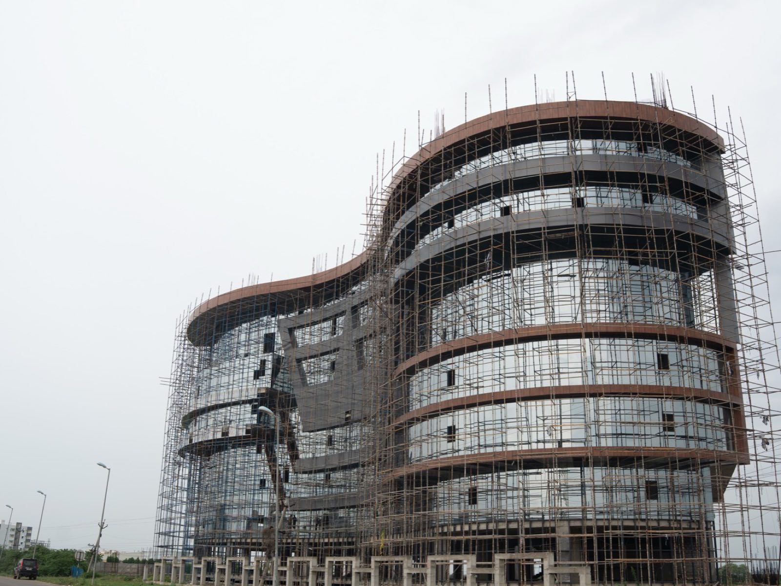 A curved high-rise frame wrapped in scaffolding