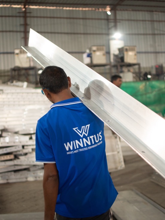 A Winntus fabricator carrying a length of aluminium panel across the shop floor