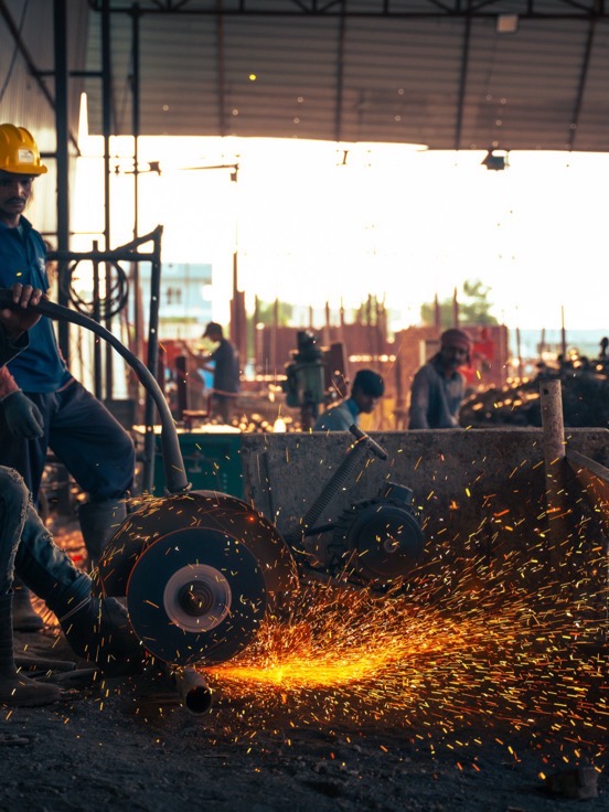 An operative cut-off grinding steel at the yard, sparks across the floor