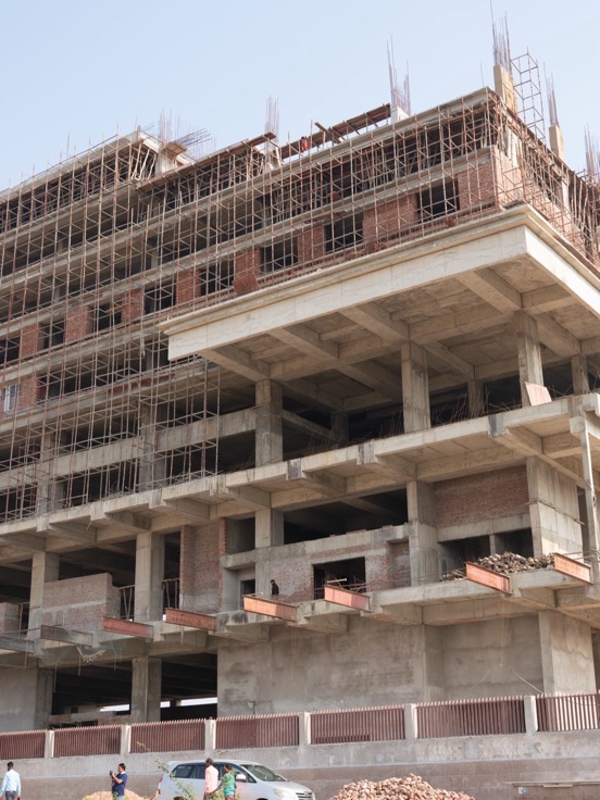 A high-rise frame rising out of slab formwork, workers on the lower decks