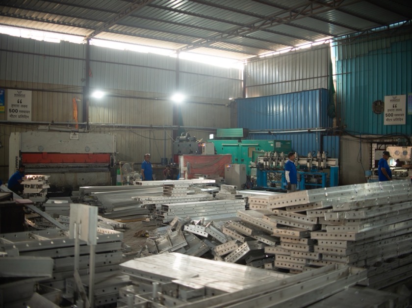 Stacks of aluminium panels in the warehouse with workers between