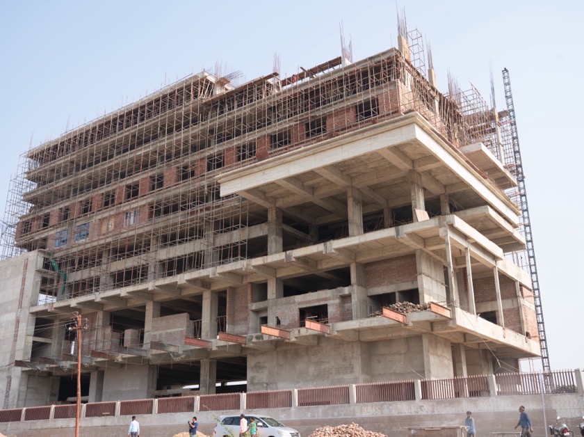 A high-rise frame with yellow edge protection and a construction lift
