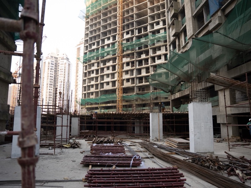Two workers carrying long reinforcement bars on site