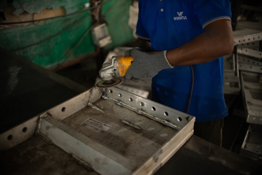 A worker stacking aluminium wall formwork panels onto a pallet in the factory