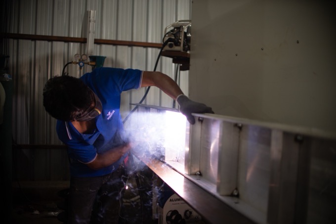 A welder in a protective helmet and apron joining aluminium formwork components